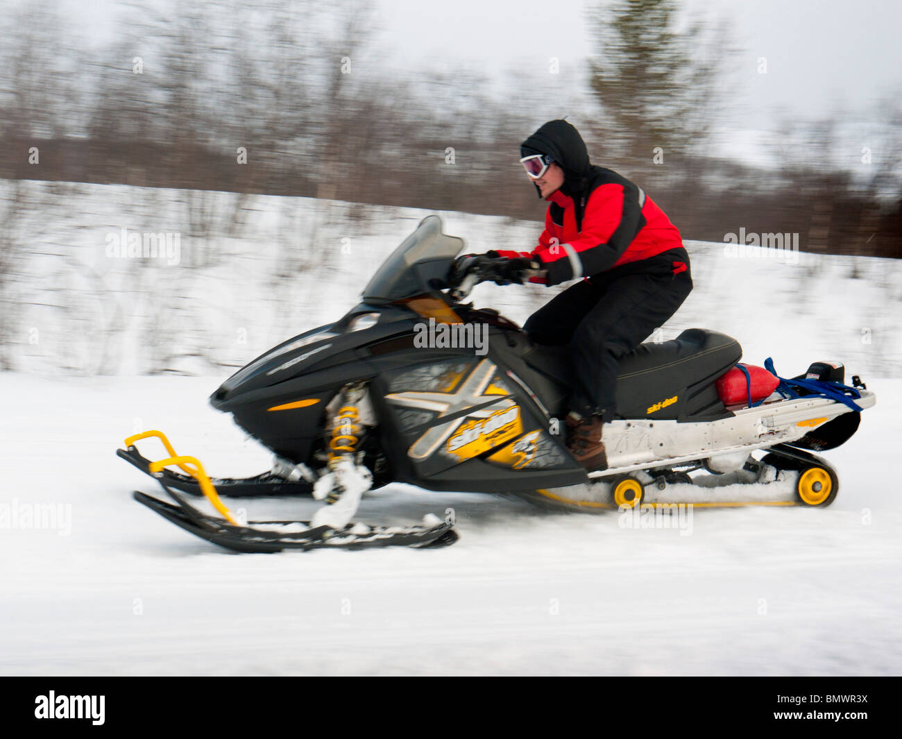 Un jeune homme conduit une motoneige à travers la neige à Kiruna, en Laponie, le nord de la Suède. Banque D'Images