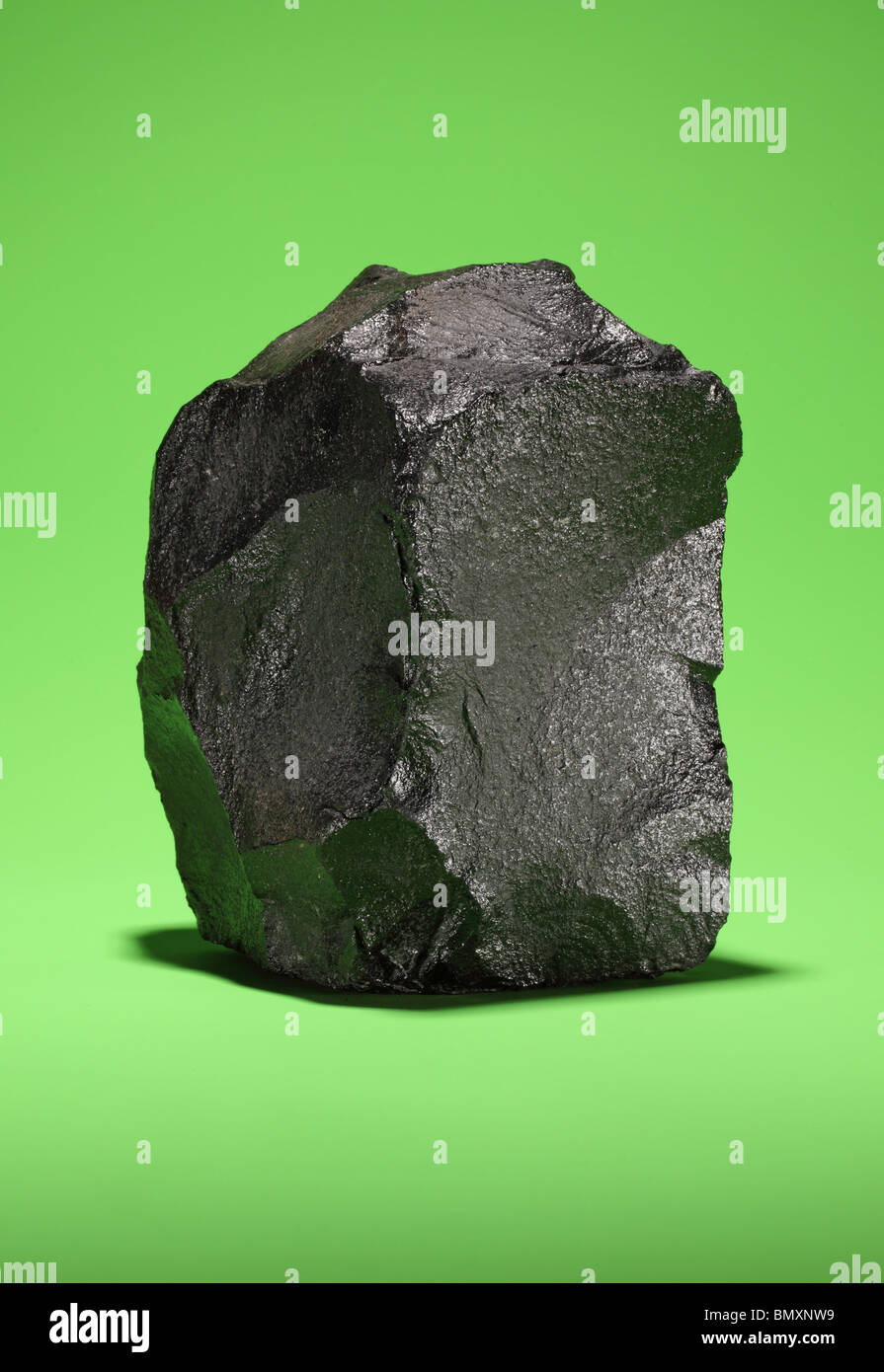 Un grand morceau de charbon bitumineux noir sur un fond vert lumineux Banque D'Images