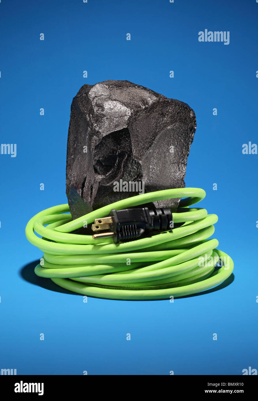 Un grand morceau de charbon noir avec une rallonge électrique vert et  bouchon rétractable autour sur un fond bleu lumineux Photo Stock - Alamy