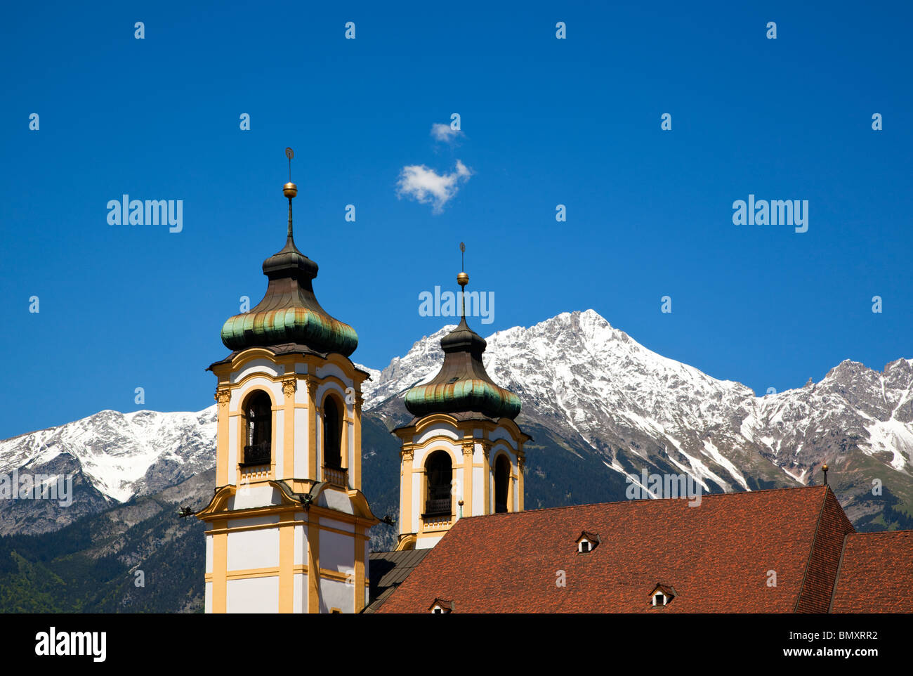 Les clochers et les toits de la basilique de Wilten à Innsbruck, les pics de Karwendel et ciel bleu avec petit nuage moelleux Banque D'Images