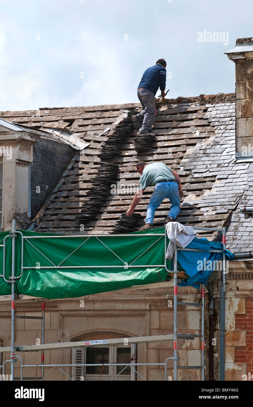 Maison de ville les travailleurs sur la dépose de l'ancienne toiture ardoises / aucun équipement de sécurité ou des casques - France. Banque D'Images