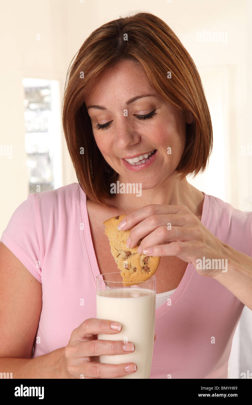 Femme buvant du lait et de manger un cookie Banque D'Images