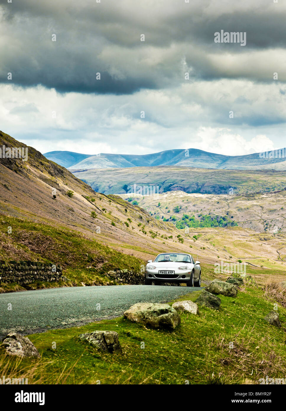 La conduite, UK, conduite de voiture de sport sur une route de montagne dans la région du Lake District, d'un voyage dans la région de Cumbria, Angleterre, Royaume-Uni Banque D'Images
