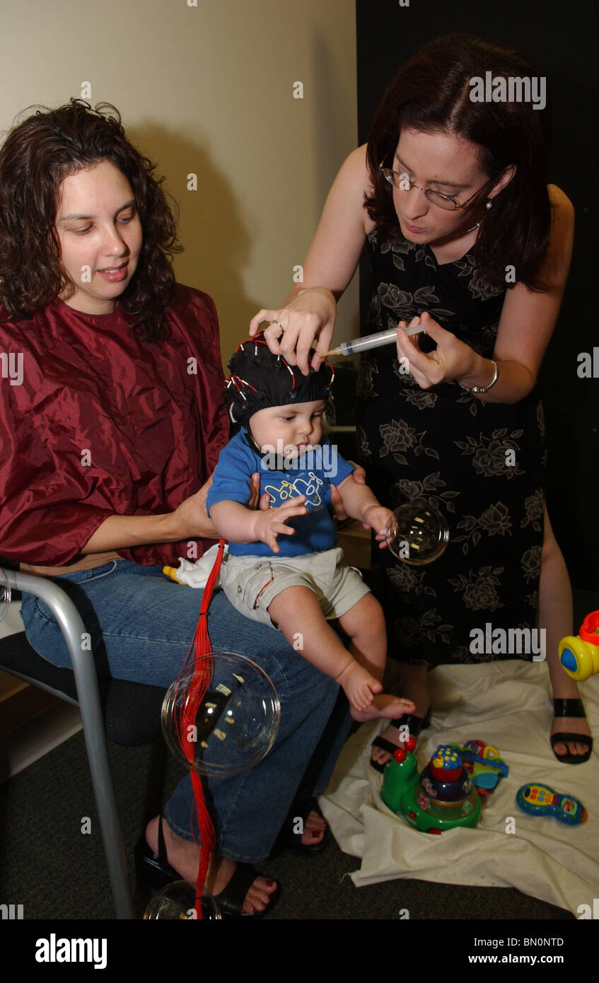 Chercheur universitaire met les électrodes sur 6-month-old boy's head avant d'onde cérébrale suivi réponse à des photographies de visages Banque D'Images