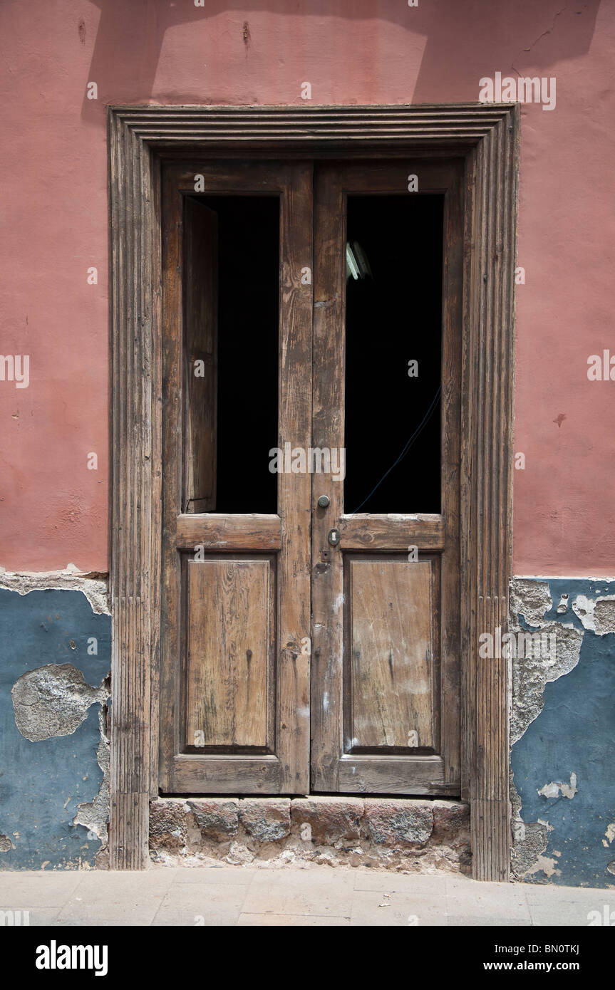 Une vieille porte en bois fermée avec des fenêtres cassées et un tube fluorescent activé dans un bâtiment à Ténérife, Espagne. Banque D'Images