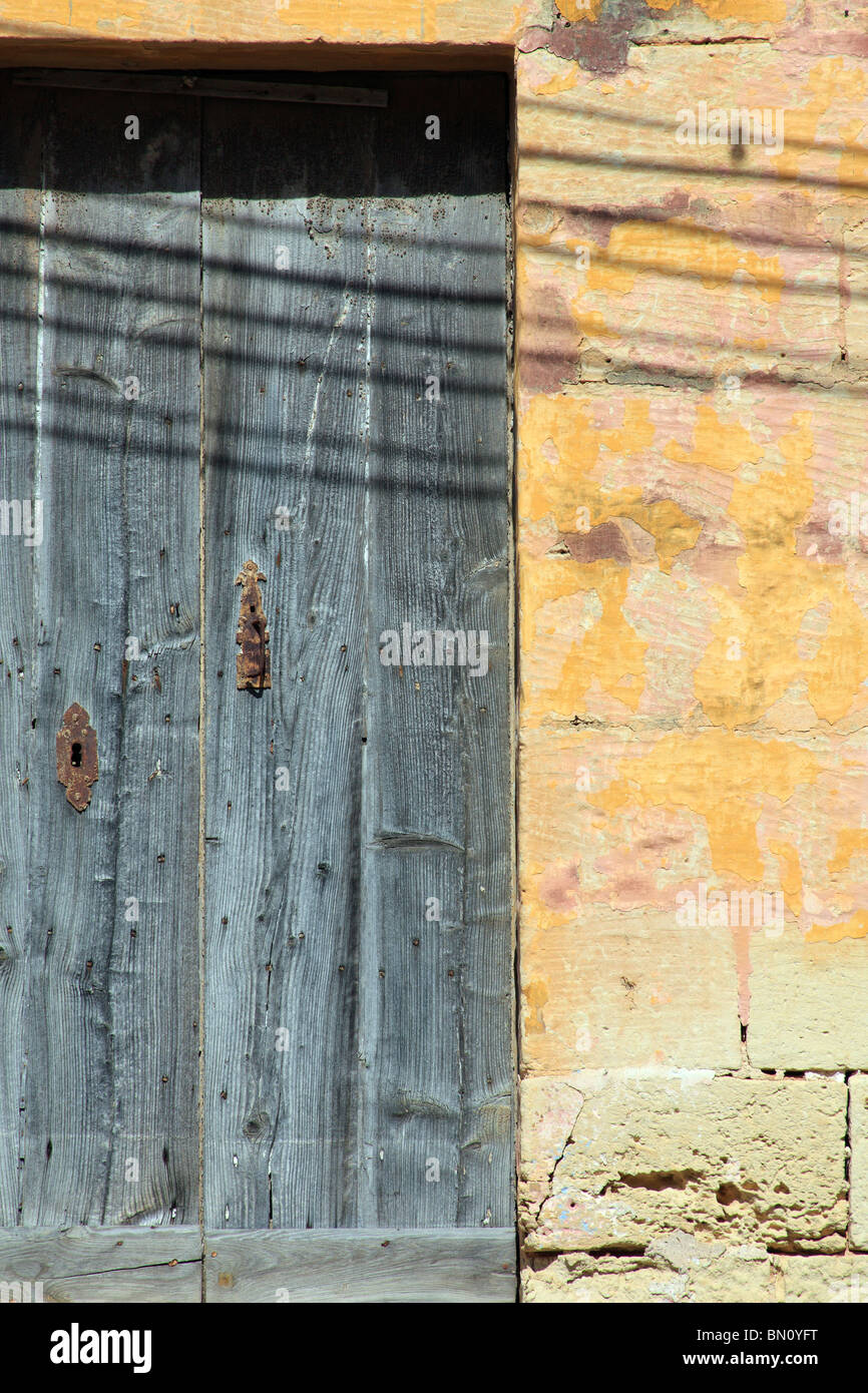 Une vieille porte en chêne patiné et décolorées avec rusty les verrous posés dans un mur en pierre jaune, Dingli, Malte Banque D'Images