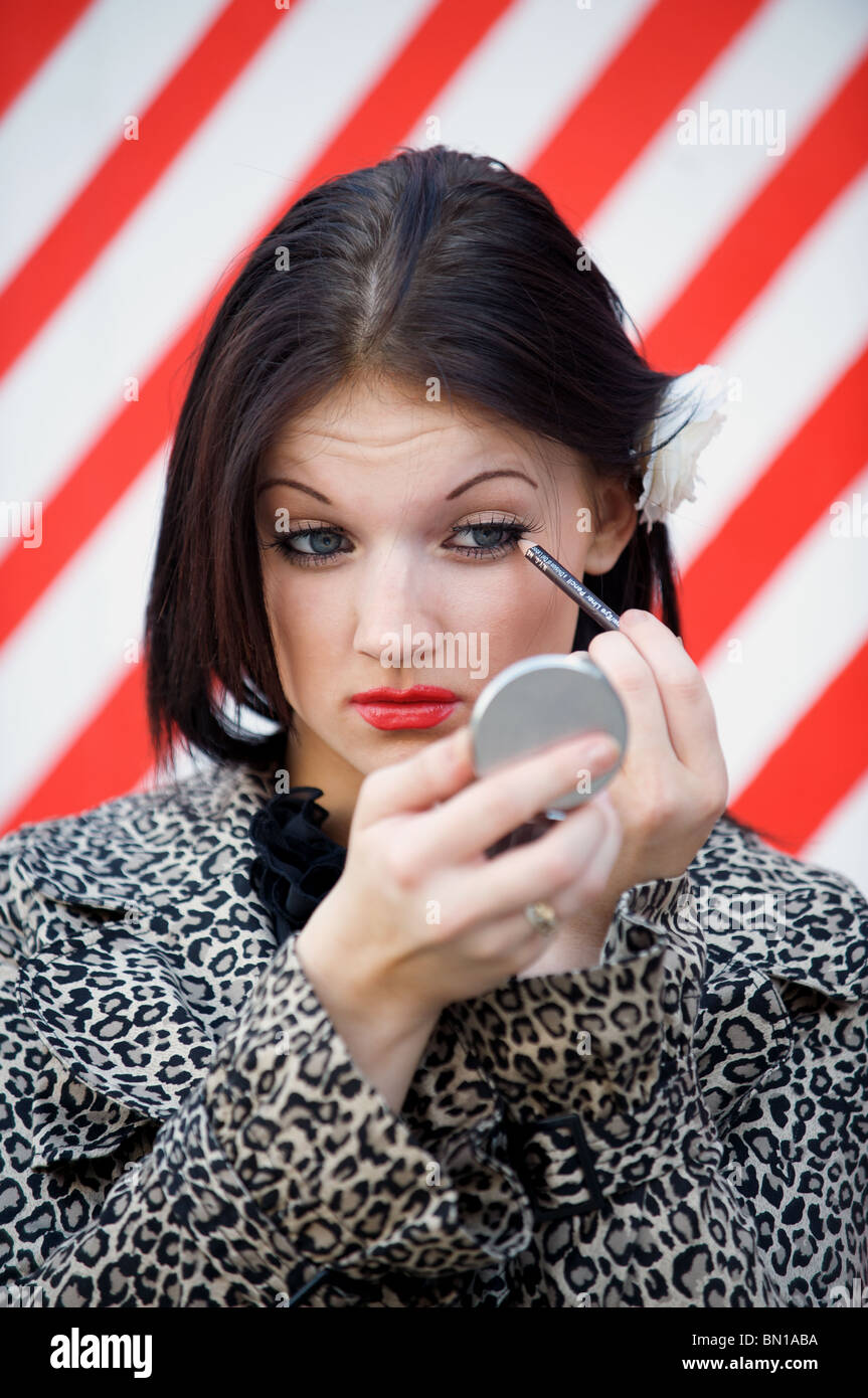 Young woman applying eye liner Banque D'Images