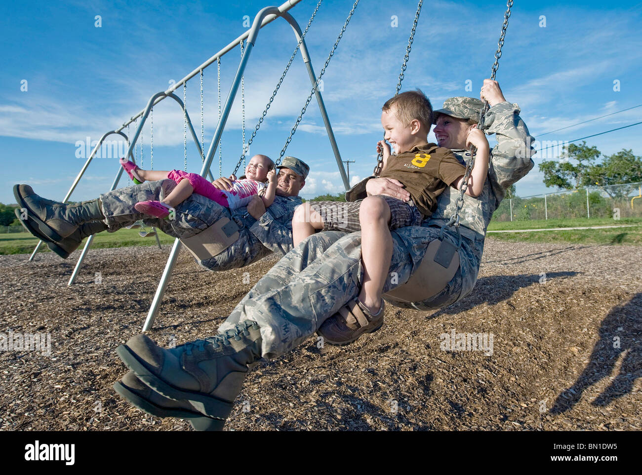 Le sergent-chef. Roldolfo Gamez et son épouse, Tech. Le Sgt. Christina Gamez, swing avec leurs enfants dans leur parc de quartier Banque D'Images