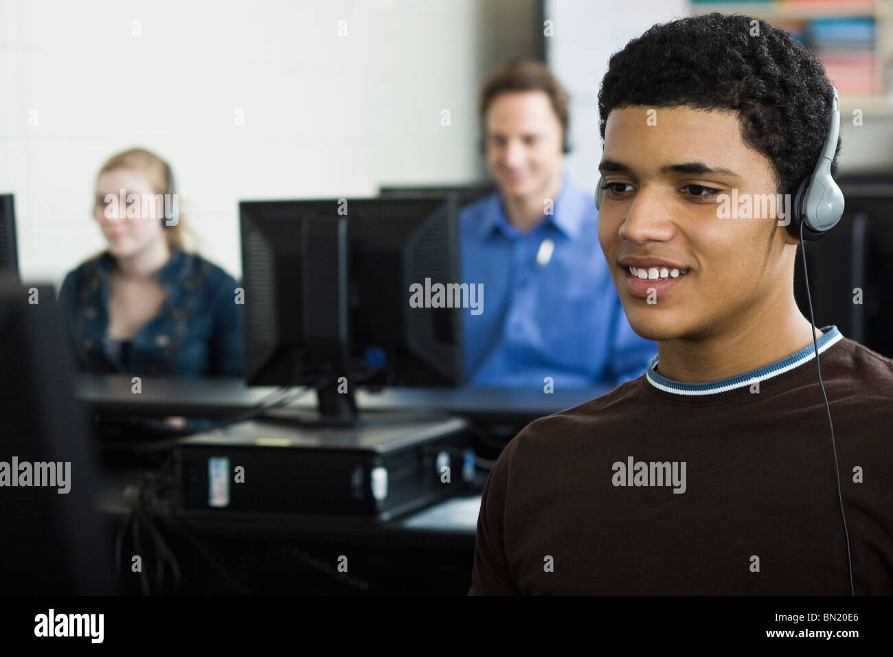 Student listening to headphones in computer lab Banque D'Images