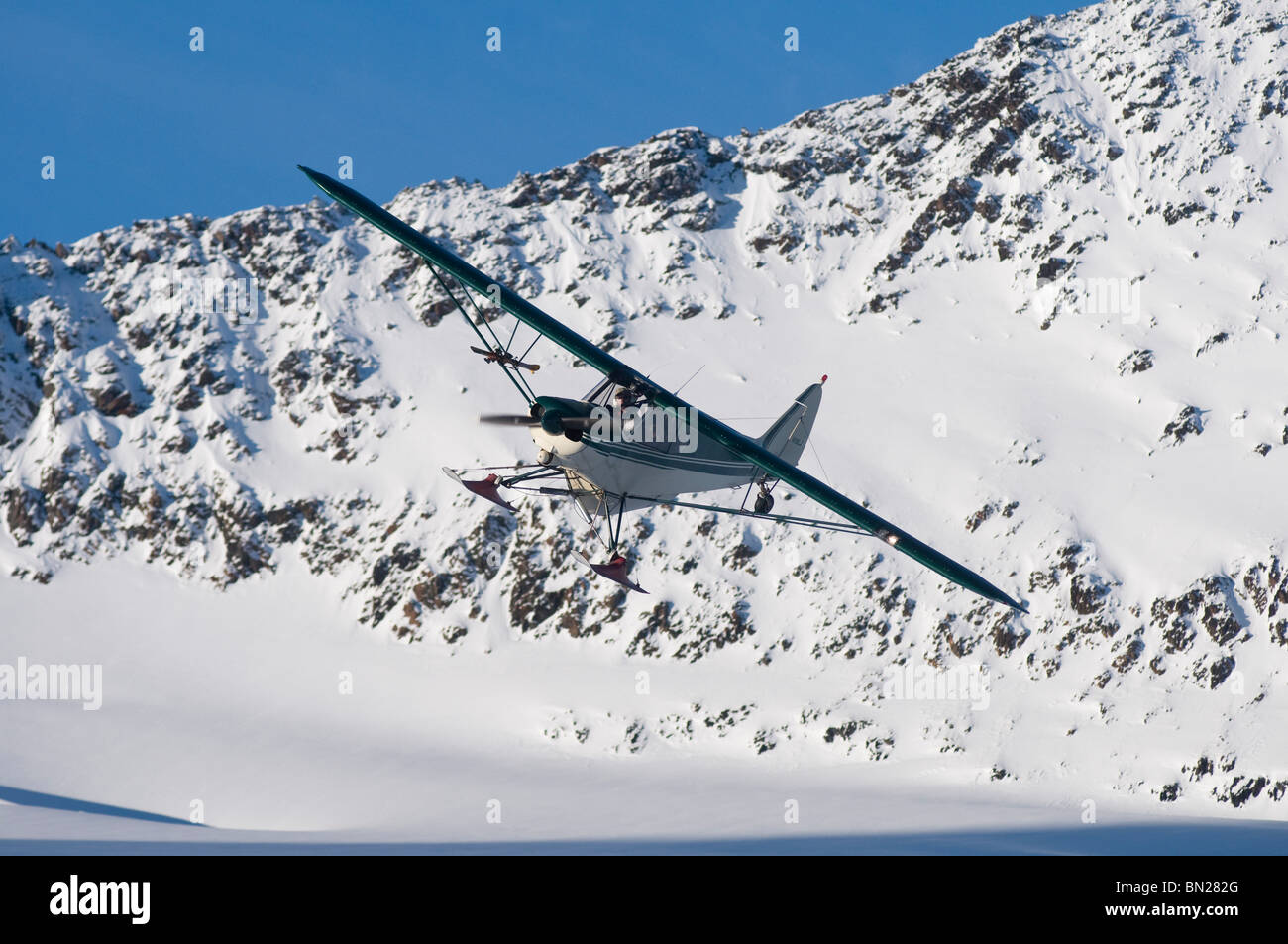 Pilote de brousse volant son Piper Super Cub sur le glacier, les montagnes Chugach Eagle, Alaska Banque D'Images