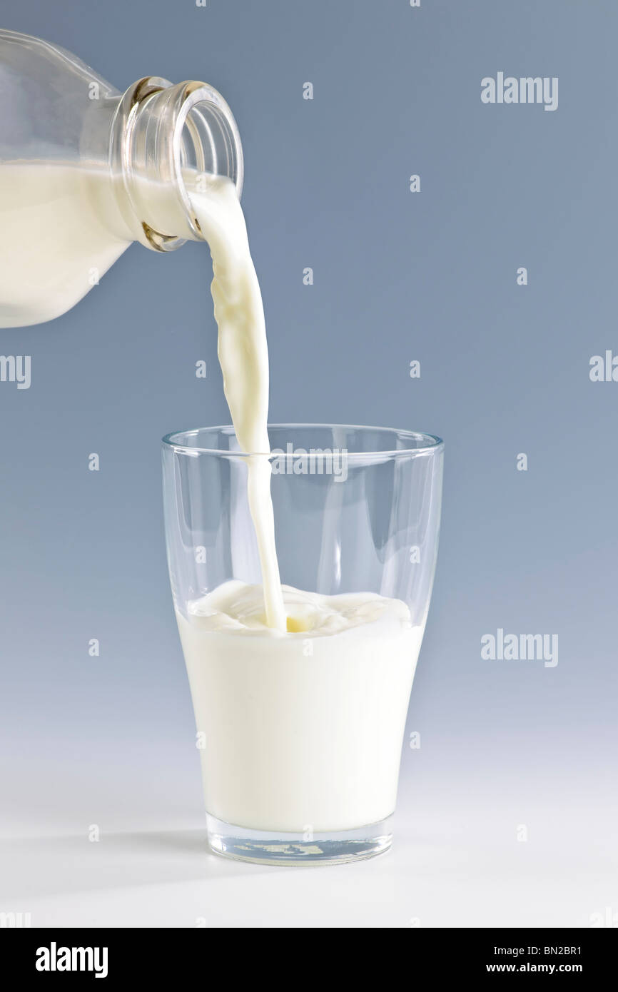 Verser le lait blanc frais de la bouteille dans un verre Banque D'Images