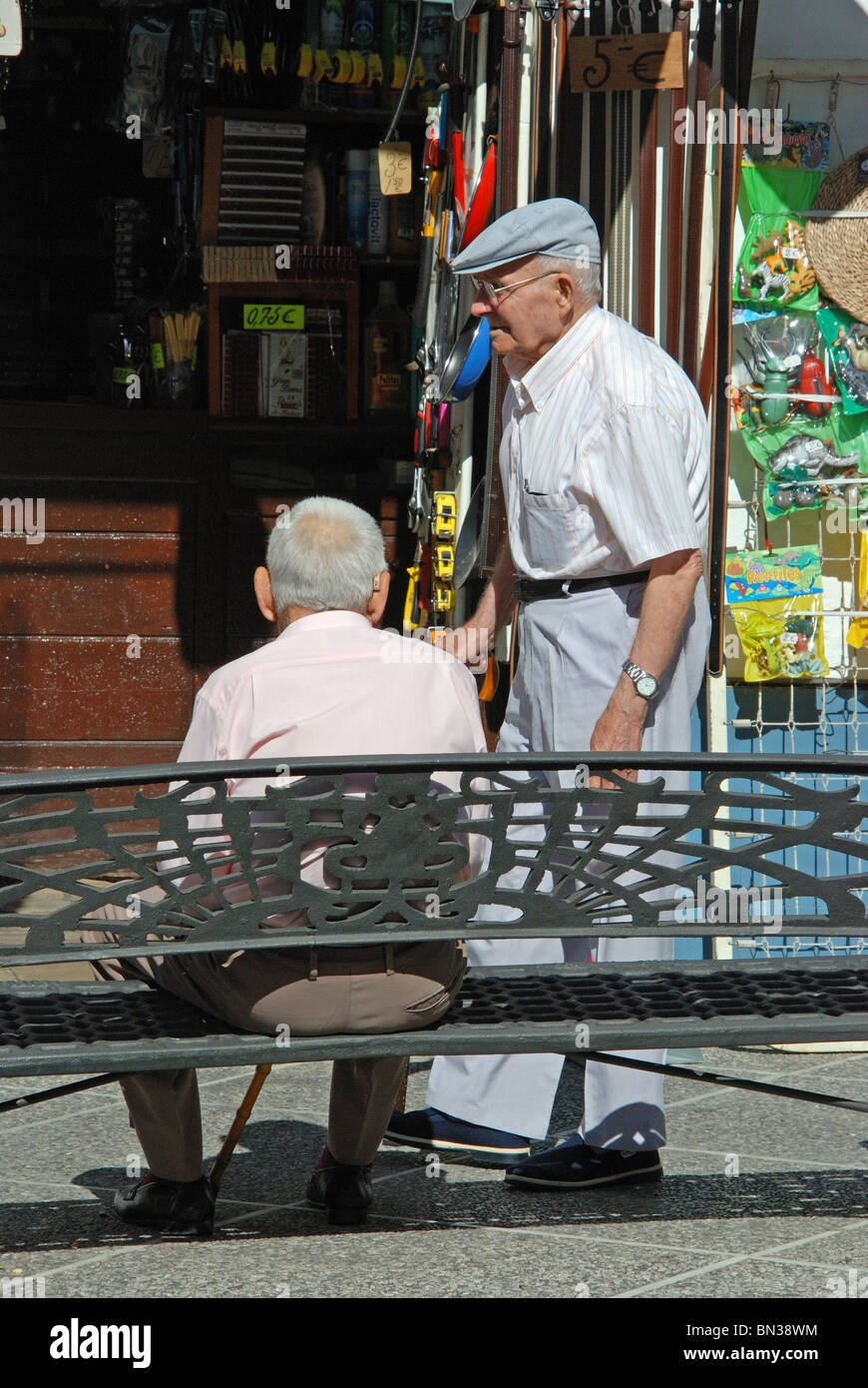 Personnes âgées L'Espagnol les hommes assis sur un banc dans la Calle Virgen de la Paz, Medina Sidonia, Province de Cadix, Andalousie, Espagne, Europe. Banque D'Images