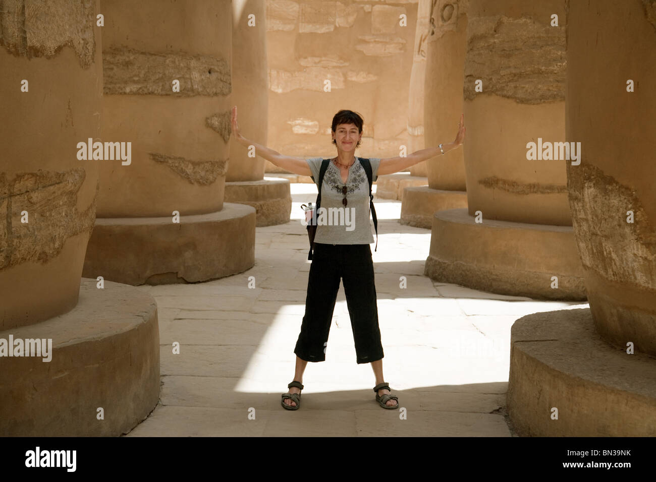 Un touriste dans la salle hypostyle 'holding up les colonnes', Temple de Karnak, Louxor, Egypte Banque D'Images