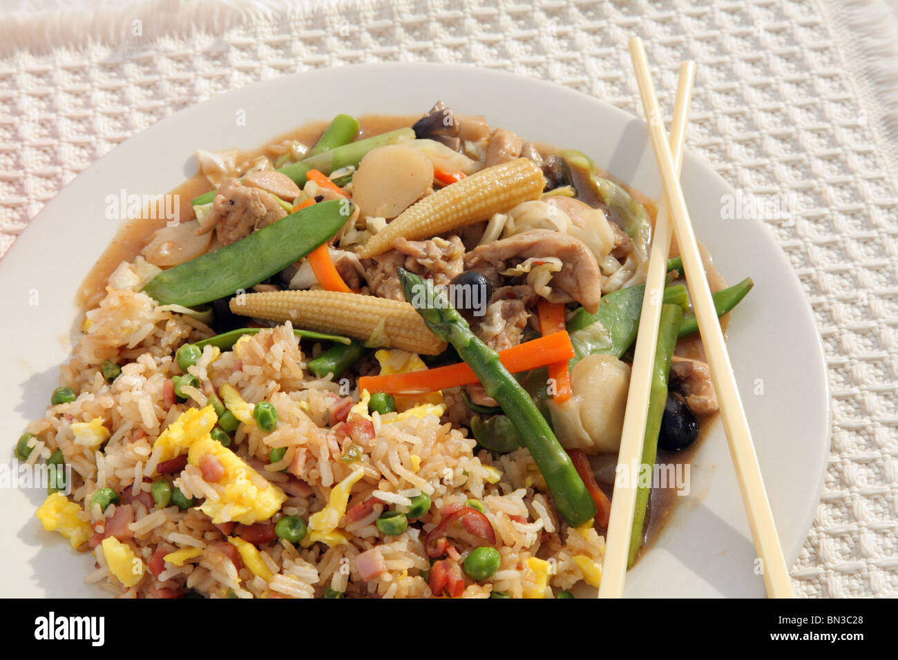 Poulet chinois teriyaki et sautés de légumes servis avec du riz et des baguettes Banque D'Images