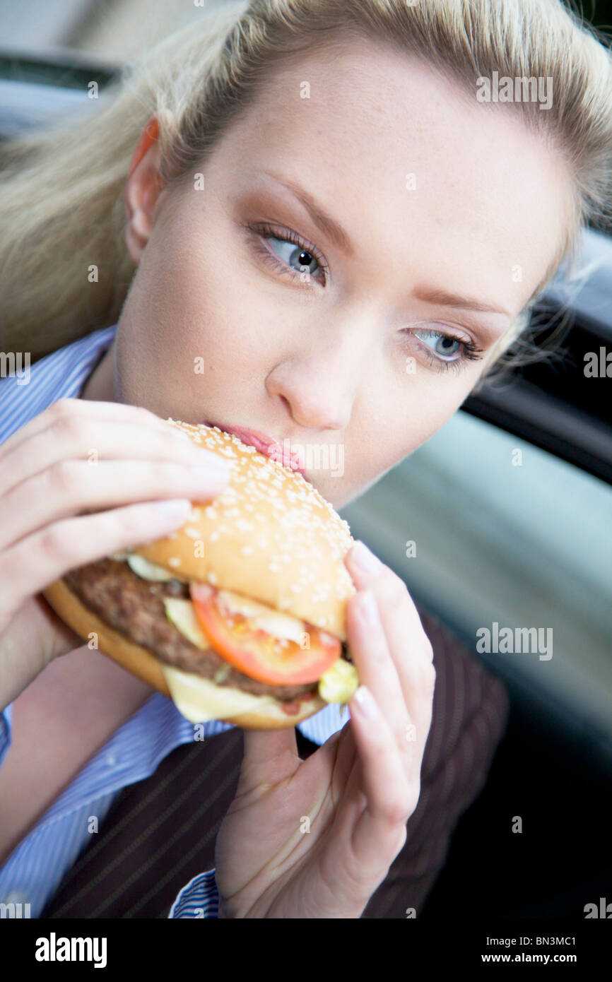 Businesswoman eating a hamburger, close-up Banque D'Images