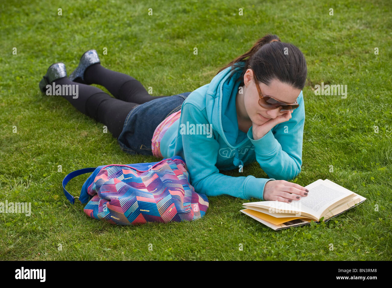 Jeune femme portant des lunettes de lecture livre sitting at Hay Festival 2010 Hay-on-Wye Powys Pays de Galles UK Banque D'Images