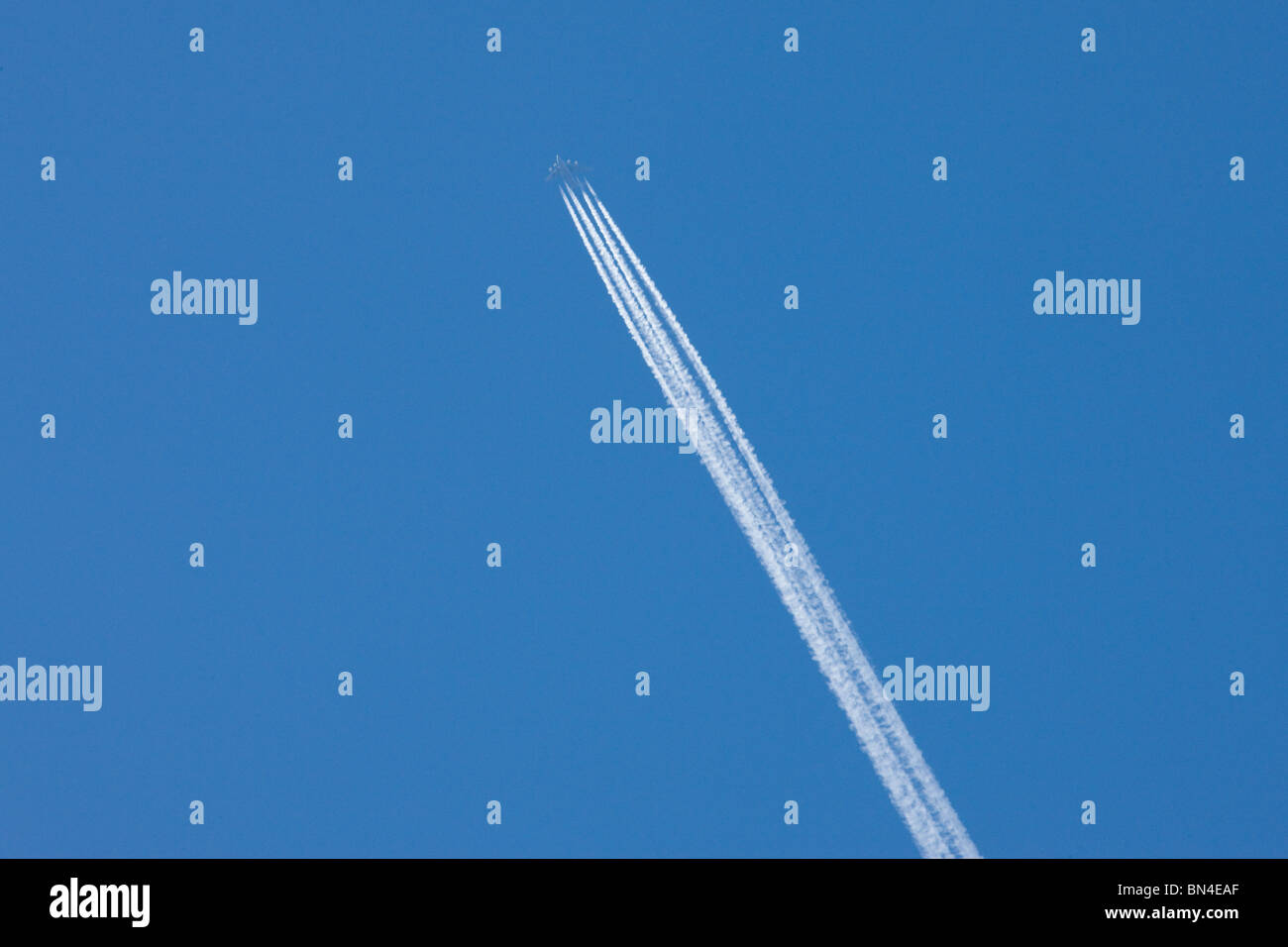 Avion de ligne / cargo avec traînées à travers un ciel bleu Banque D'Images