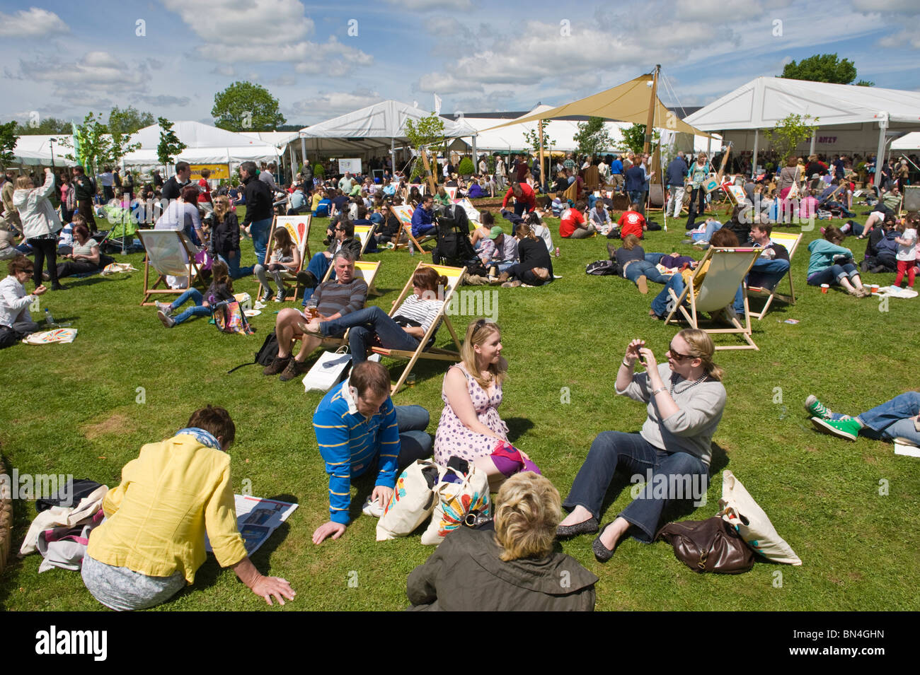 Des foules de gens se détendre assis sur l'herbe dans le soleil d'été à Hay Festival 2010 Hay-on-Wye Powys Pays de Galles UK Banque D'Images