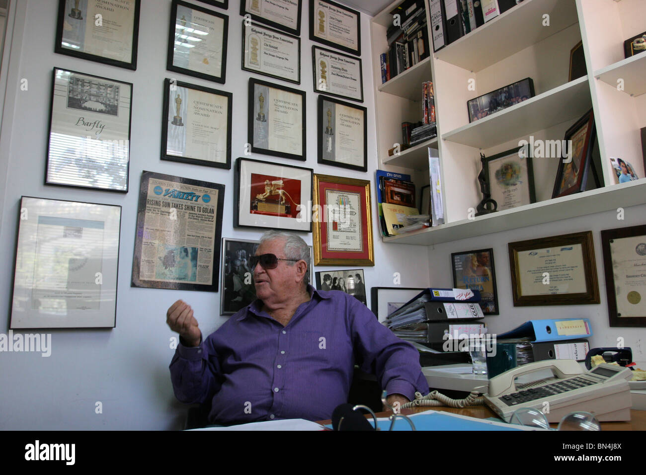 Producteur et réalisateur israélien Menahem Golan regarde ses nombreuses récompenses, accroché au mur de son bureau à Tel-Aviv. Banque D'Images