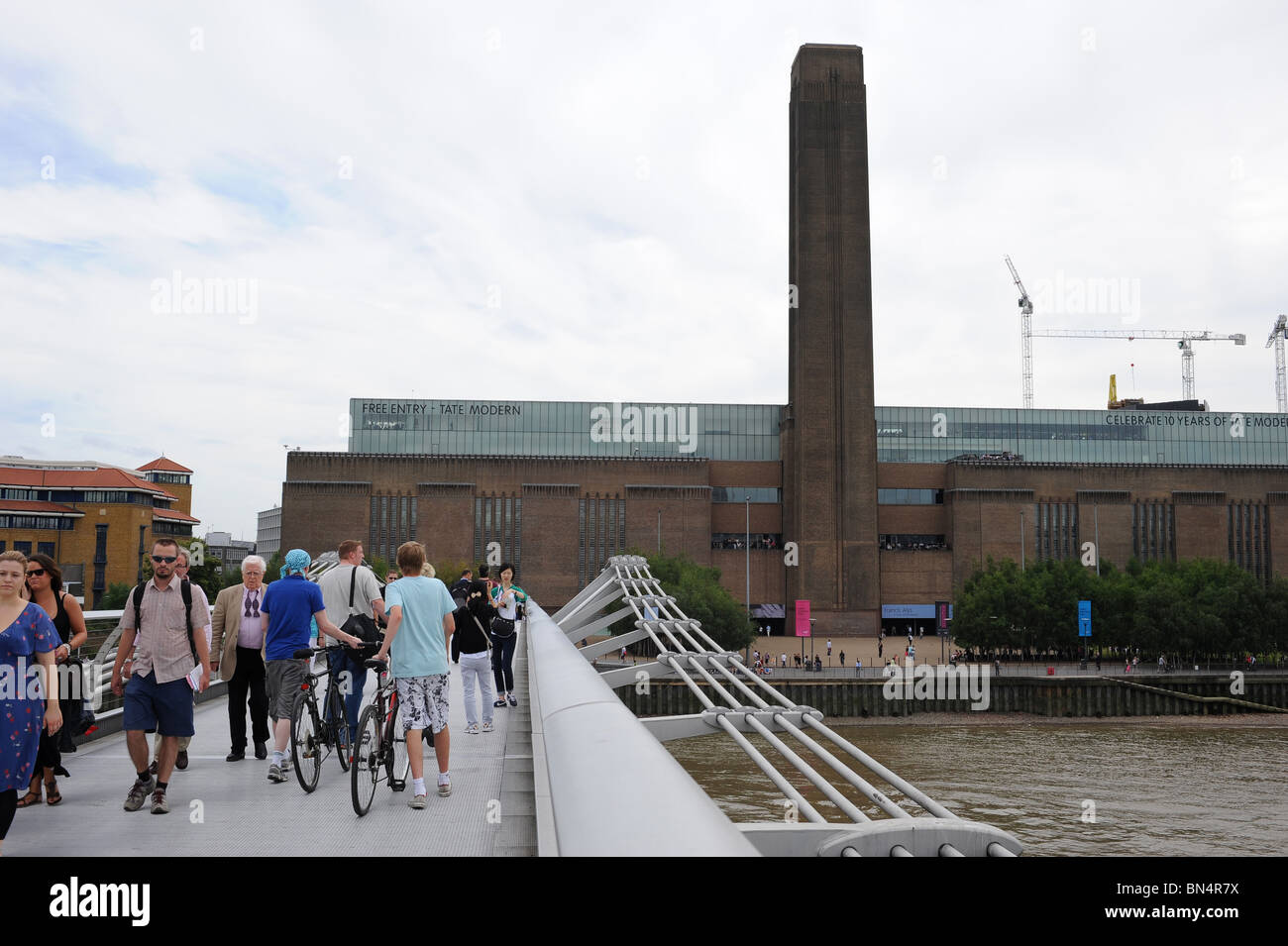 Vue de la Tate Modern Art Gallery et personnes traversant le pont du Millénaire. Southbank, Londres. Banque D'Images