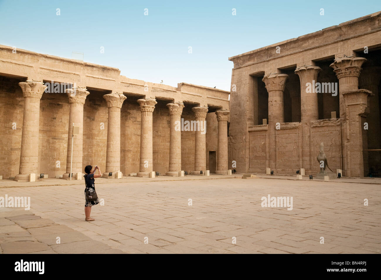 Une femme prend une photo touristique dans l'avant-cour, le temple d'Horus à Edfou, Haute Egypte Banque D'Images