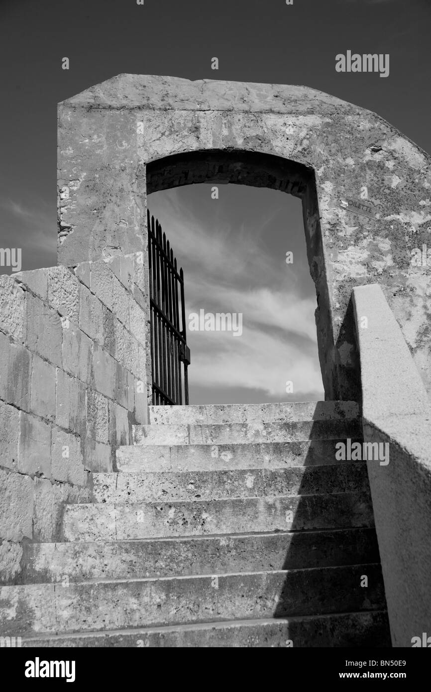 Image en noir et blanc de l'escalier menant à la porte vers le ciel et nuages Banque D'Images