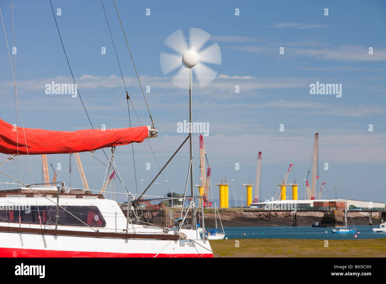 Un yacht avec une petite éolienne en face de la construction site pour Dong Energy's éoliennes en mer. Banque D'Images