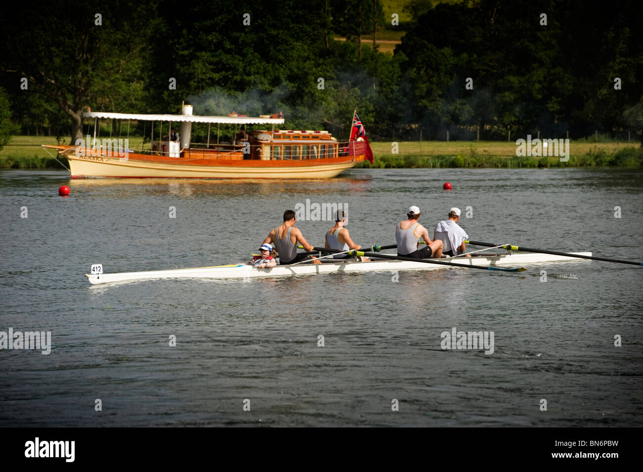 Au Henley Royal Regatta une équipe de rameurs compétitifs rangée avec une Tamise traditionnel en bois sur le bateau à vapeur banque loin Banque D'Images