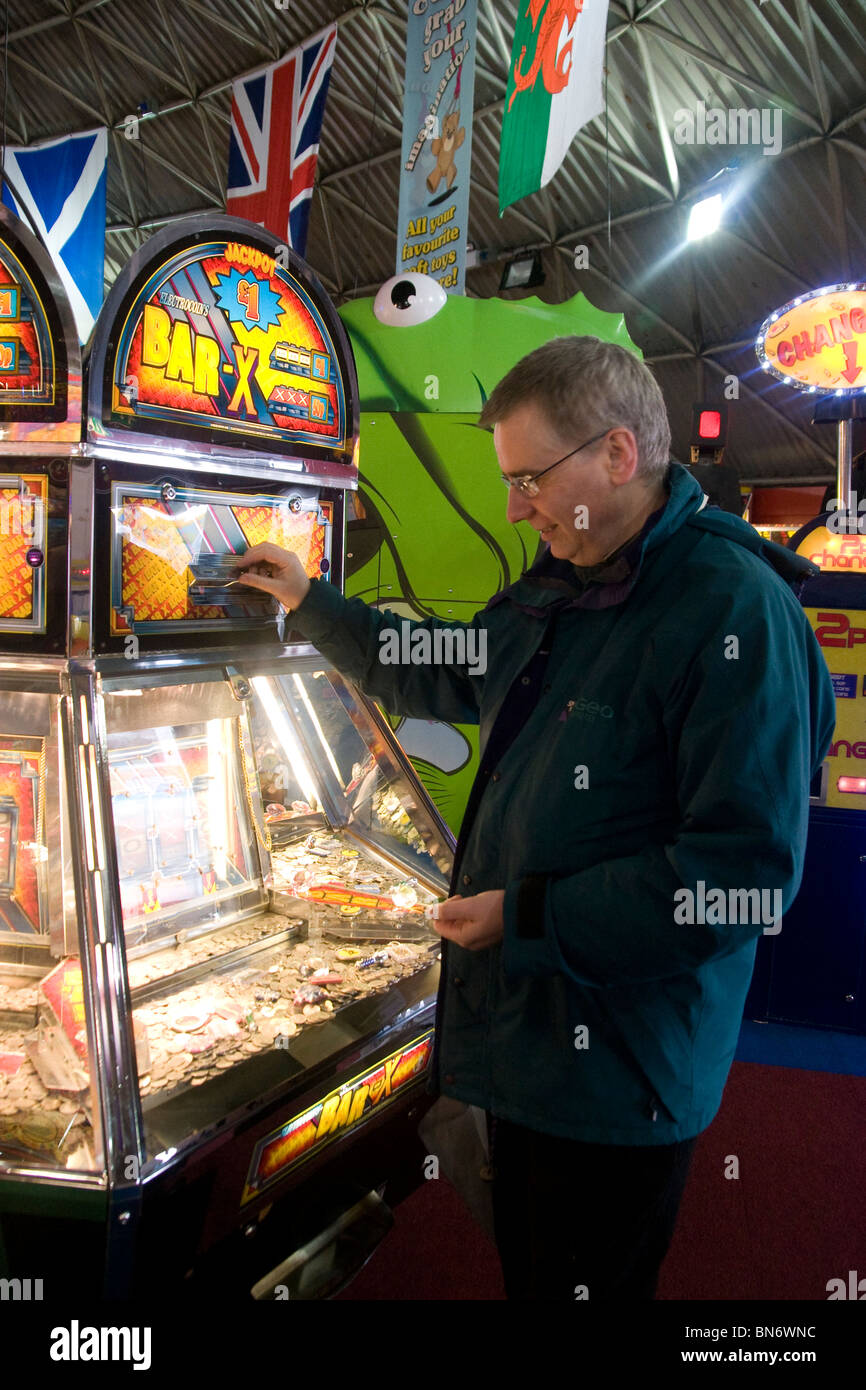 L'homme de hasard sur Penny tombe dans la machine de jeux électroniques sur la jetée de Brighton Banque D'Images