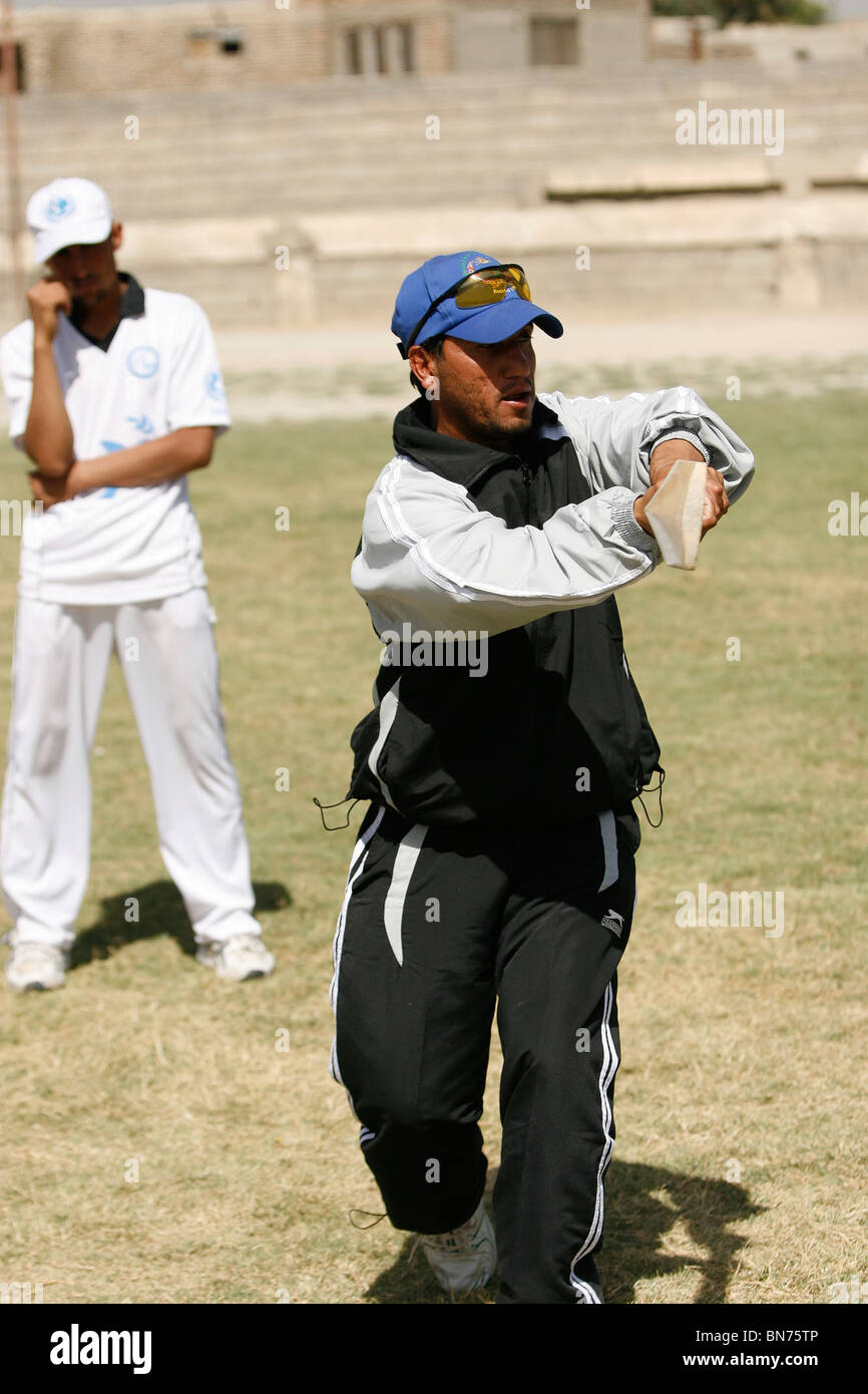 Batteur afghane enseigne aux enfants comment tenir une batte de cricket à Kaboul en Afghanistan Banque D'Images
