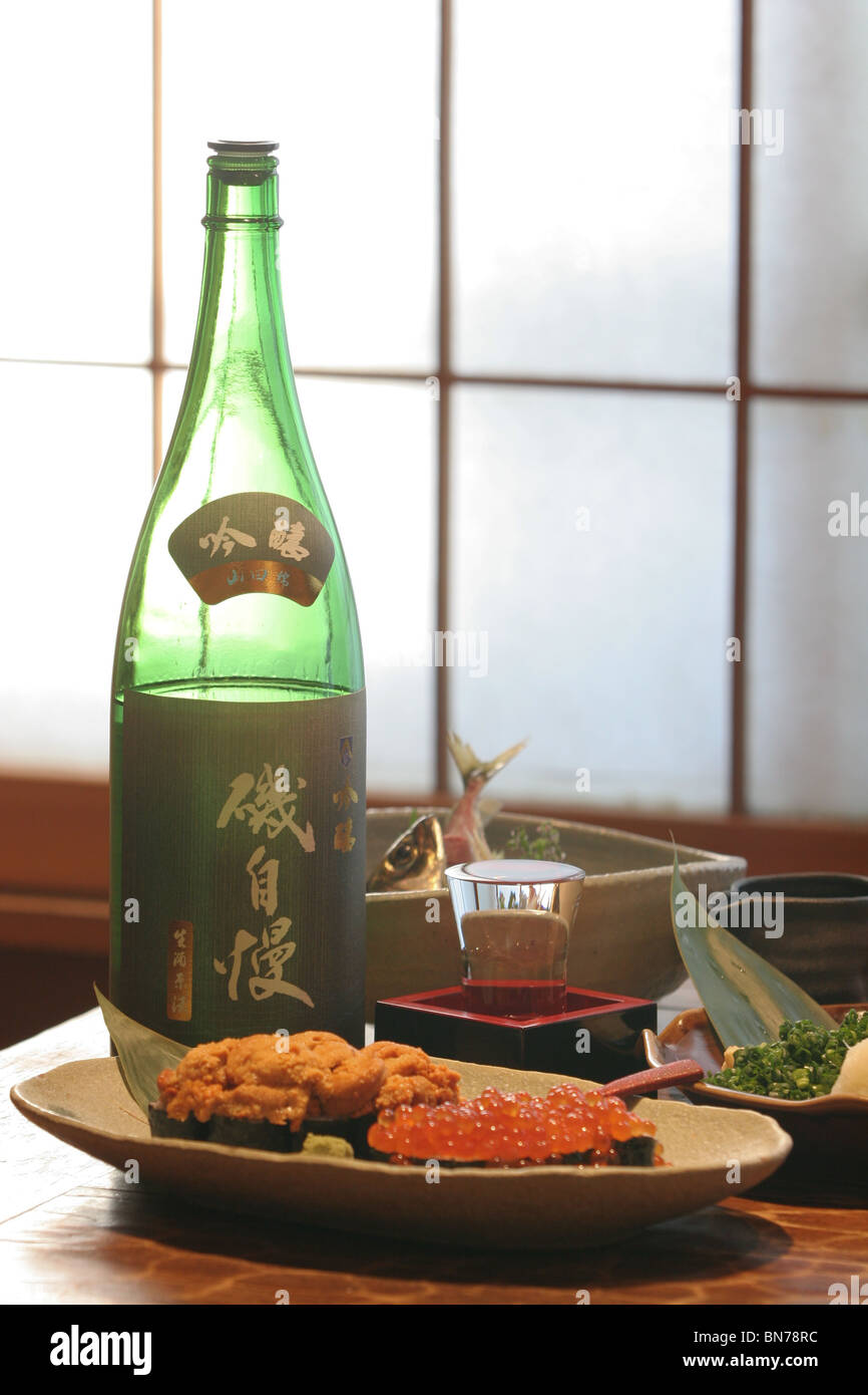 Une plaque d'ikura (œufs de saumon) et uni (oursin) , à côté d'une bouteille de saké dans un restaurant japonais Banque D'Images