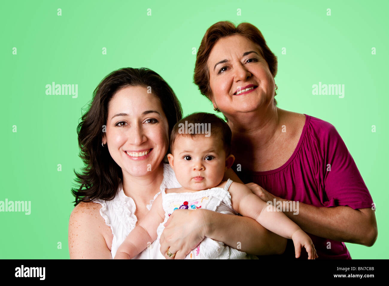 Beautiful happy trois 3 générations de Young Hispanic Latina Femmes, grand-mère, mère et petite fille, sur le vert. Banque D'Images