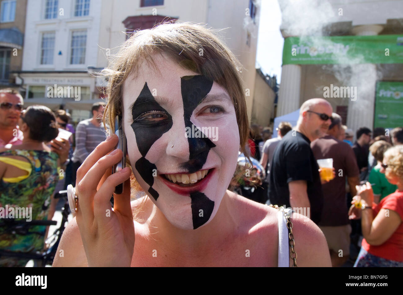 Une Brighton Festival Fringe street perfomer en plein maquillage sur son téléphone portable entre montre à Brighton, East Sussex. Banque D'Images