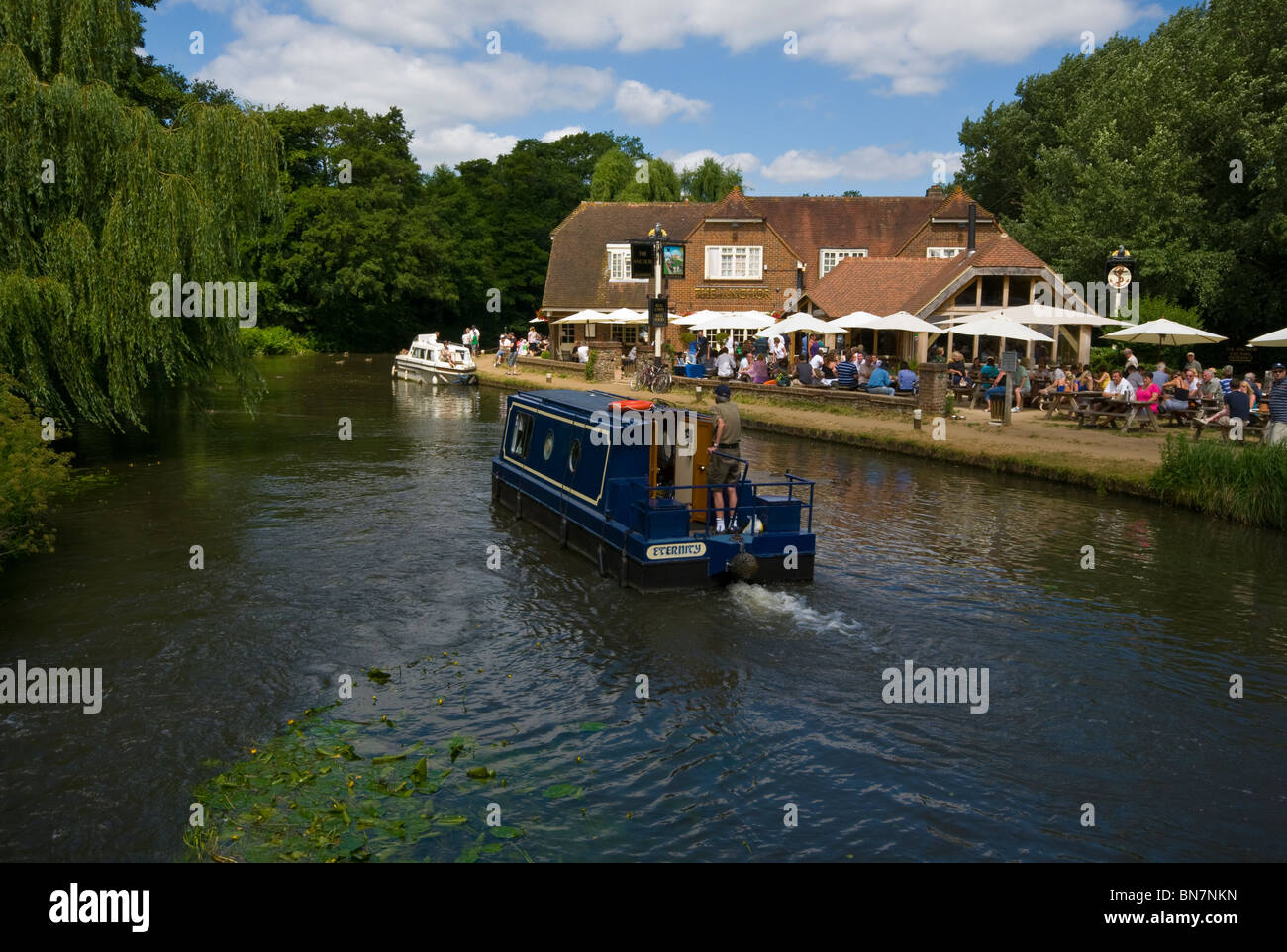 Un étroit canal boat 15-04 passant le Anchor Pub sur la rivière Wey Pyrford Surrey England Banque D'Images
