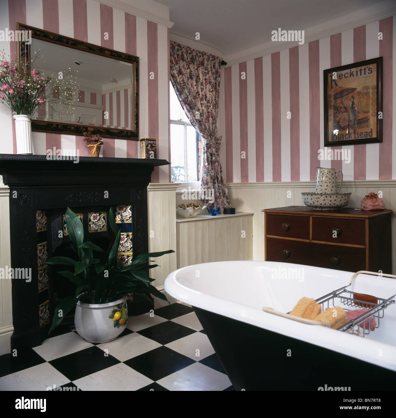 Papier peint à rayures roses et une baignoire dans la salle de bain pays  avec noire fonte cheminée et plancher en vinyle blanc +noir Photo Stock -  Alamy