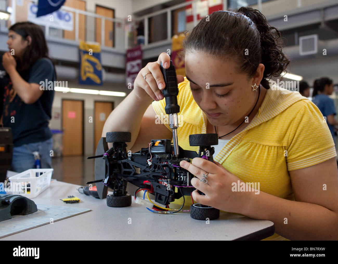 Au lycée fille serre la vis sur voiture radio-commandée en classe de robotique. Banque D'Images