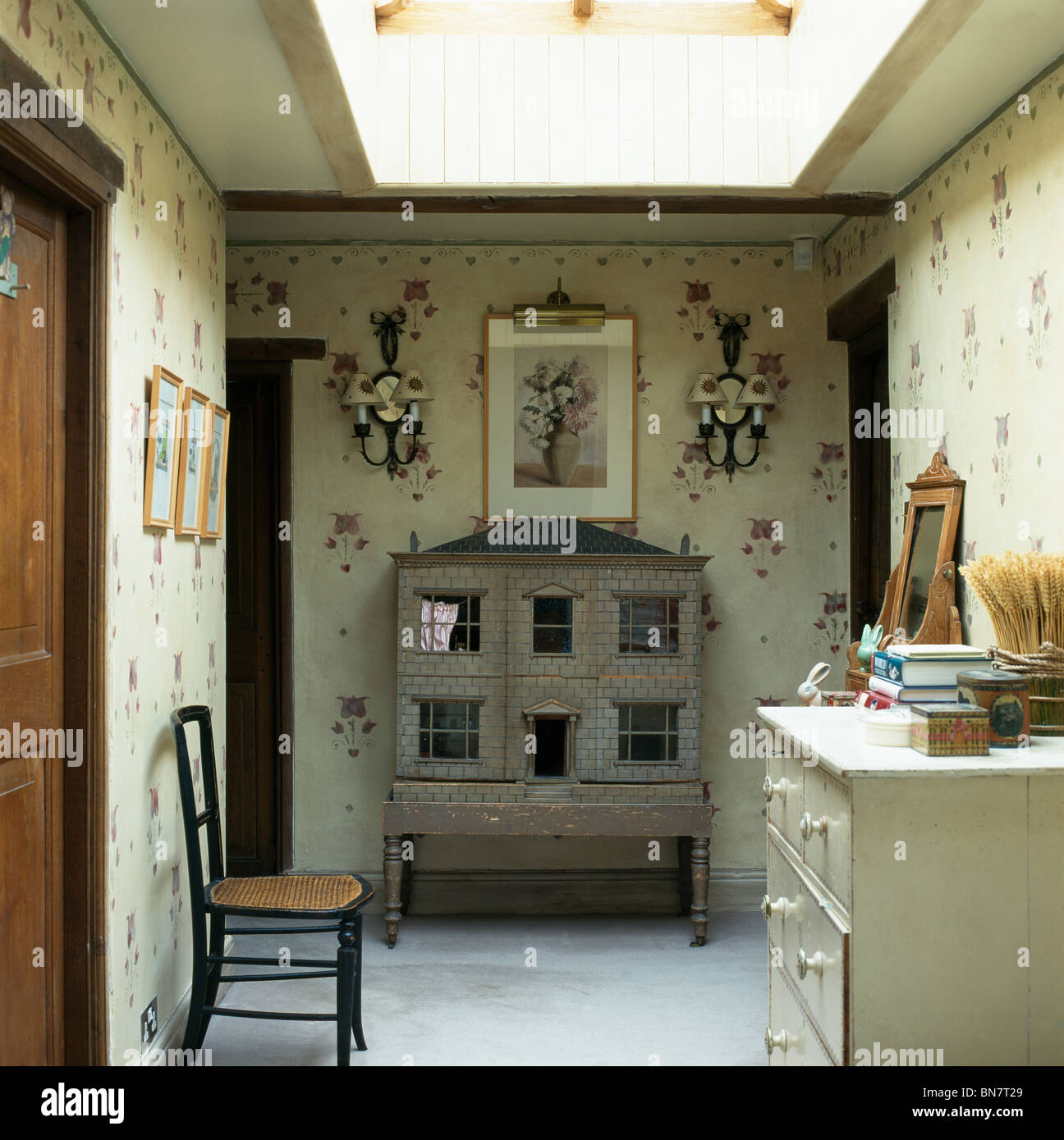 Poupées anciennes maison sur petit palier avec murs floraux peints à la main et chaise ancienne et la poitrine de tiroirs Banque D'Images
