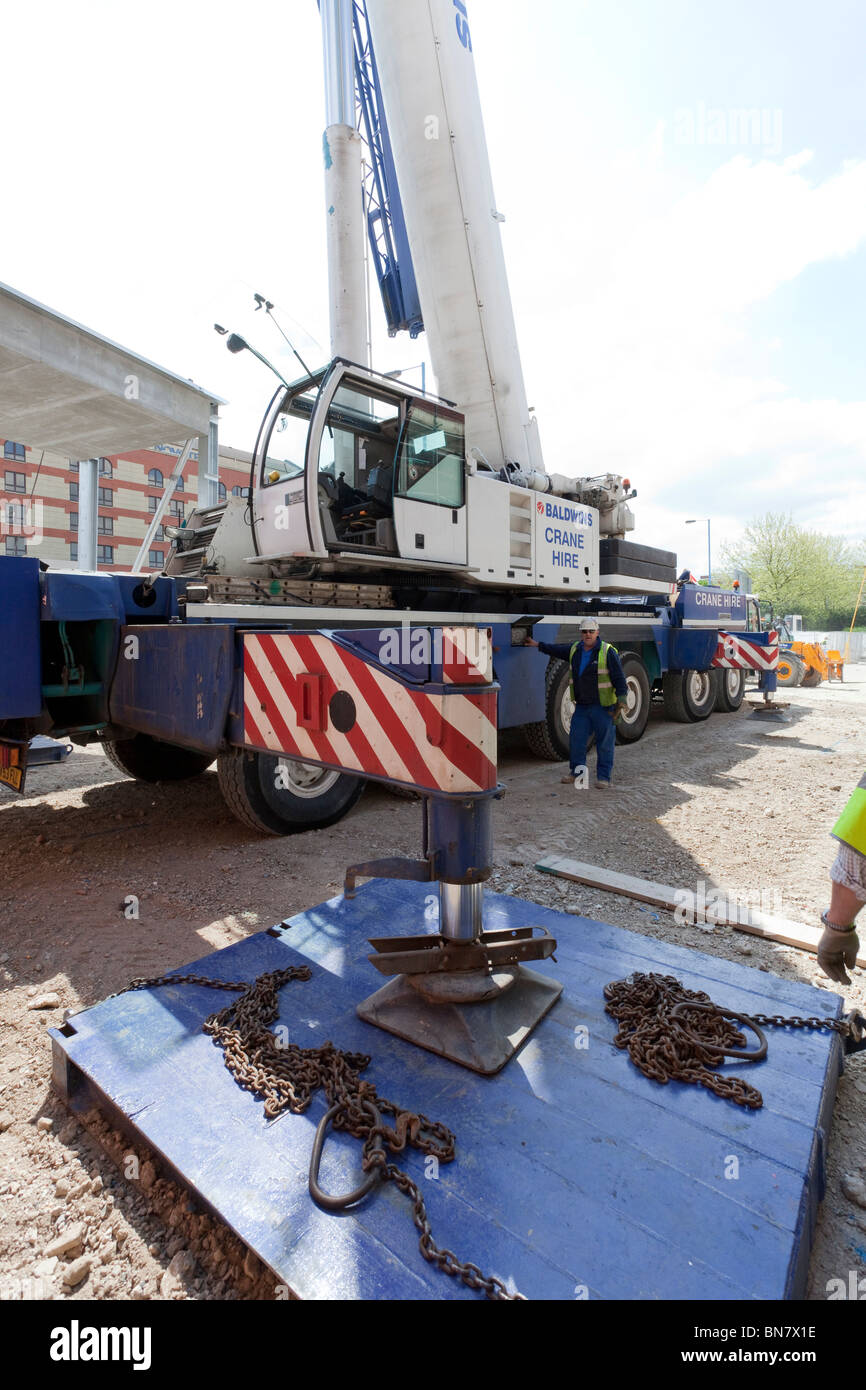 La mise en place des stabilisateurs pour une grande grue mobile sur un site de construction Banque D'Images