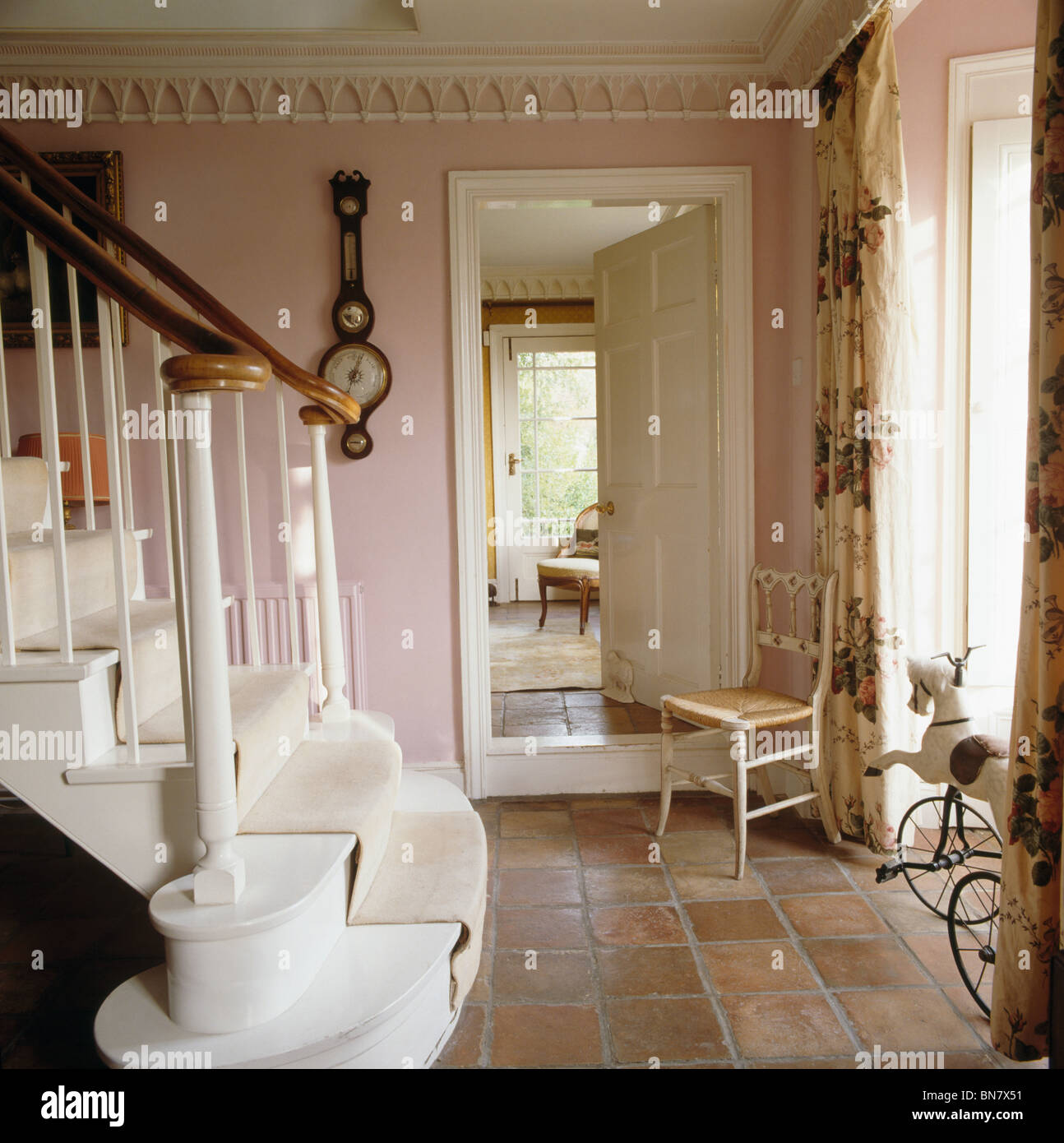 Chaise ancienne à côté d'ouvrir la porte de salle à manger en pays rose hall avec moquette crème sur escalier peint en blanc Banque D'Images
