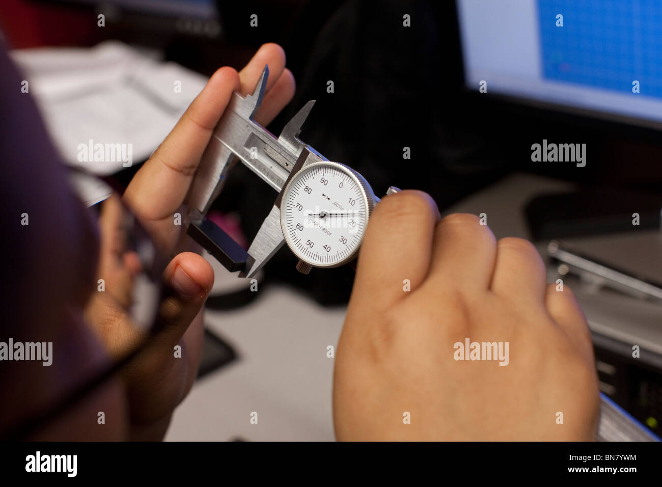 Lycéen utilise un étrier pour prendre une mesure en première classe d'ingénierie Banque D'Images