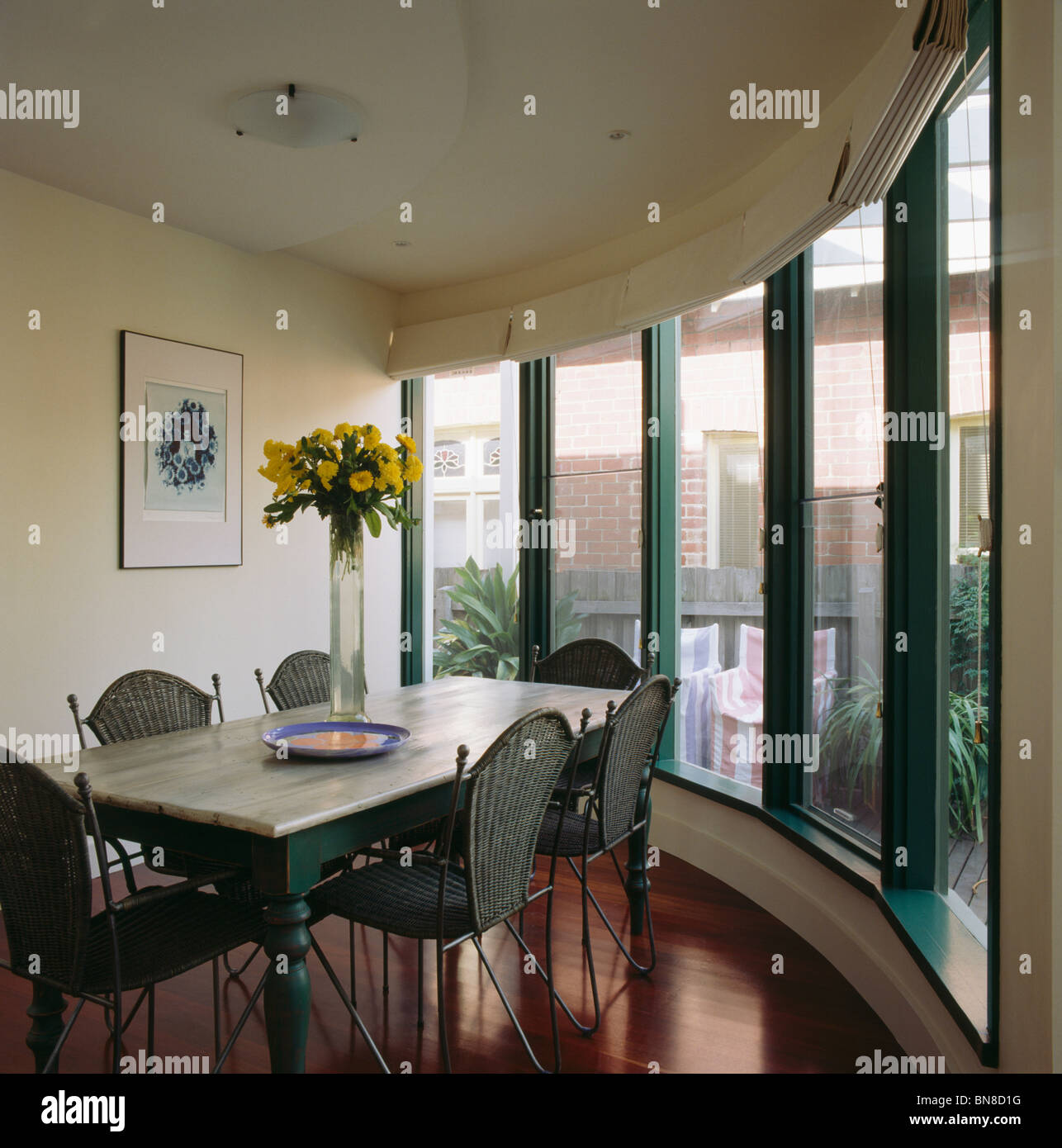 Table en marbre et des chaises en osier dans la salle à manger moderne avec des fenêtres avec cadres peints en vert Banque D'Images