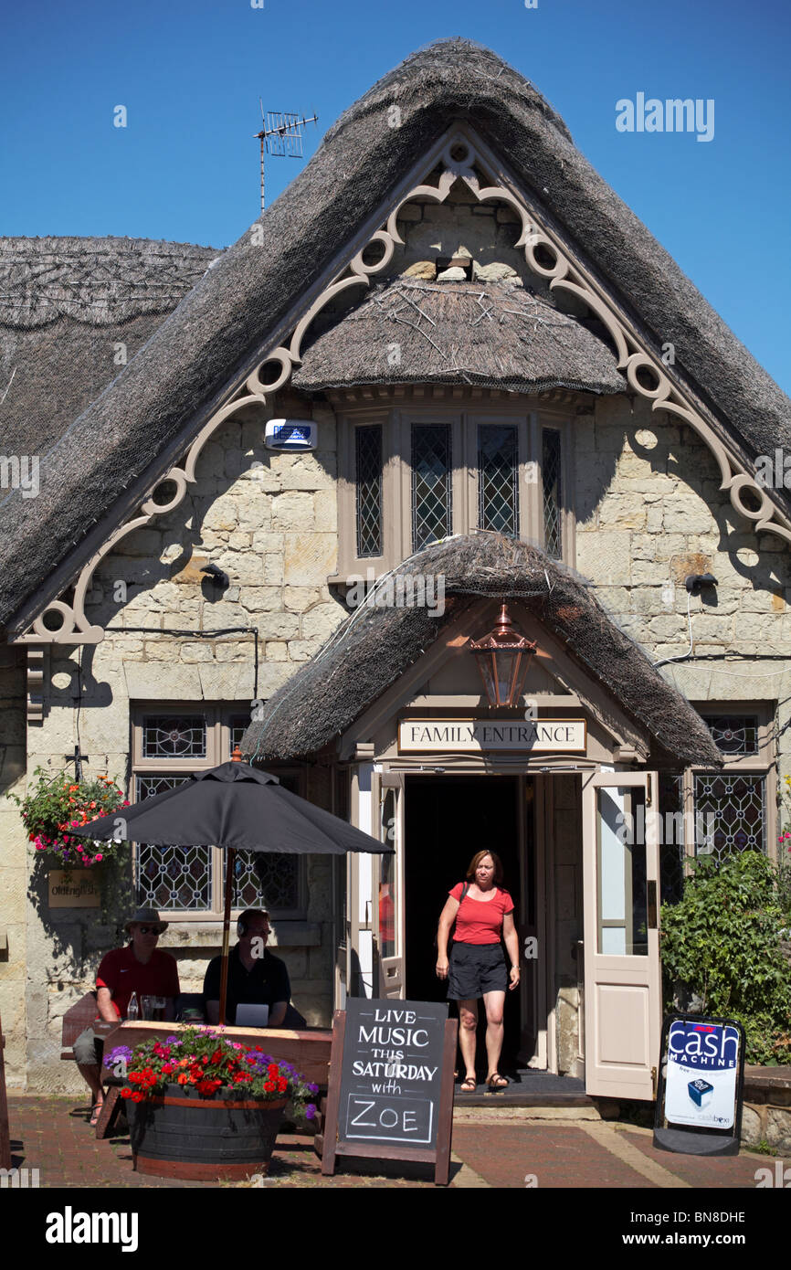 Femme quittant le pub Crab Hotel Thatched par la porte d'entrée familiale à Shanklin, île de Wight, Hampshire Royaume-Uni en juin Banque D'Images