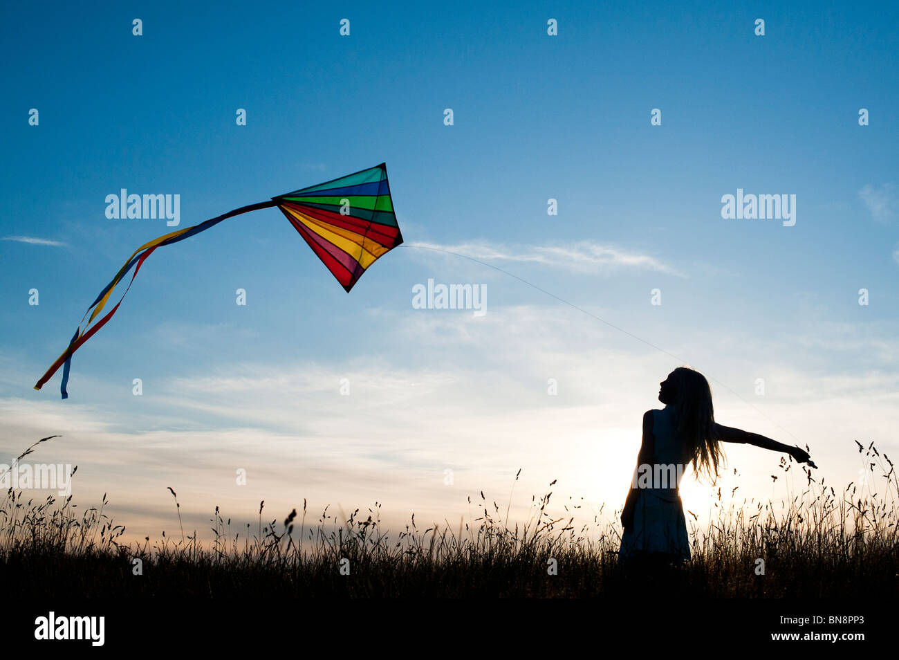 Jeune fille s'amusant voler un cerf-volant multicolore dans la campagne anglaise. Silhouette Banque D'Images