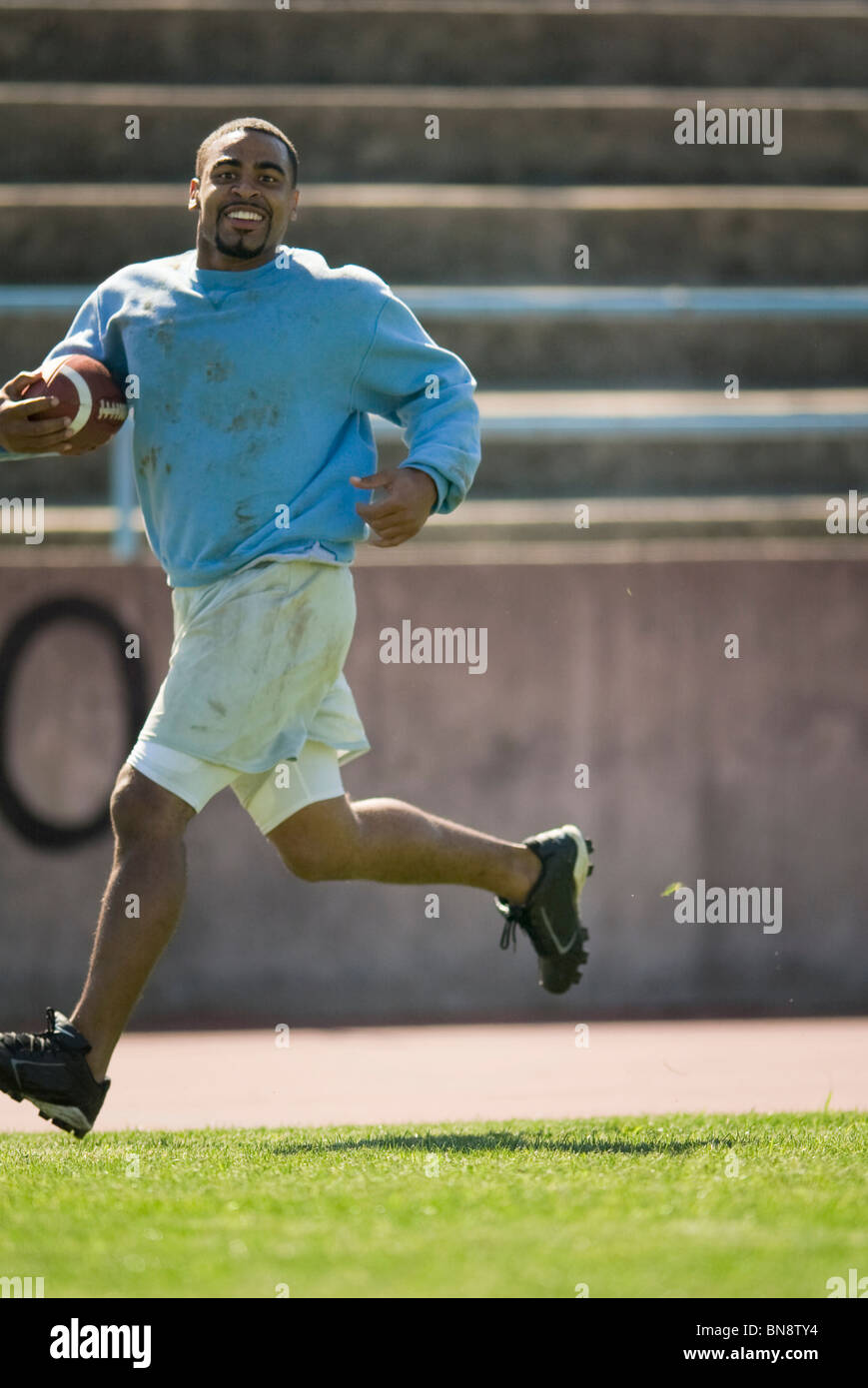 Homme qui court avec le football Banque D'Images