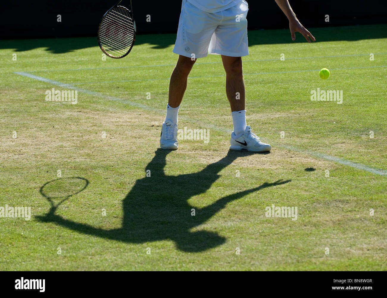 Ombre d'un joueur de rebondir la balle avant de servir au cours de la Tennis de Wimbledon 2010 Banque D'Images