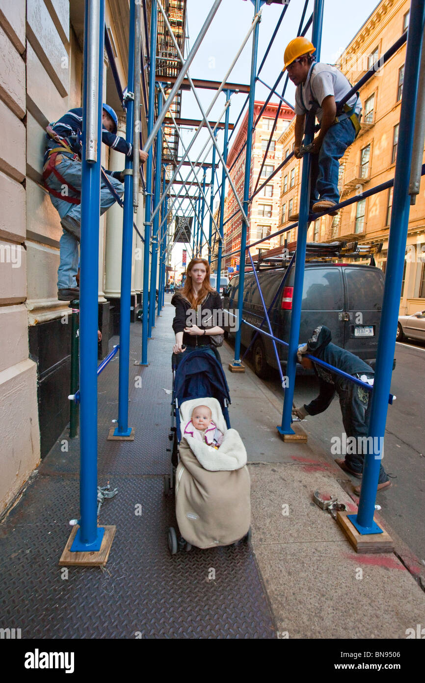 Femme avec poussette de bébé, les hommes de l'assemblage des échafaudages, Tribeca, New York Banque D'Images
