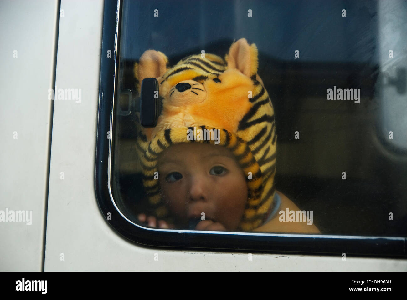 Enfant sur un minibus portant un chapeau tigre Banque D'Images