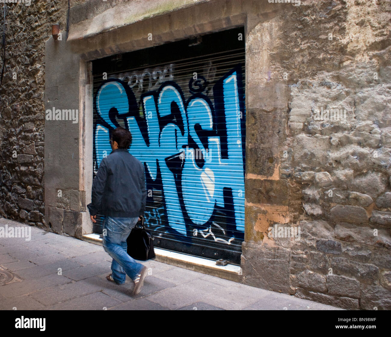 Homme MARCHANT PASSÉ Graffiti sur un obturateur dans une rue de Barcelone Banque D'Images