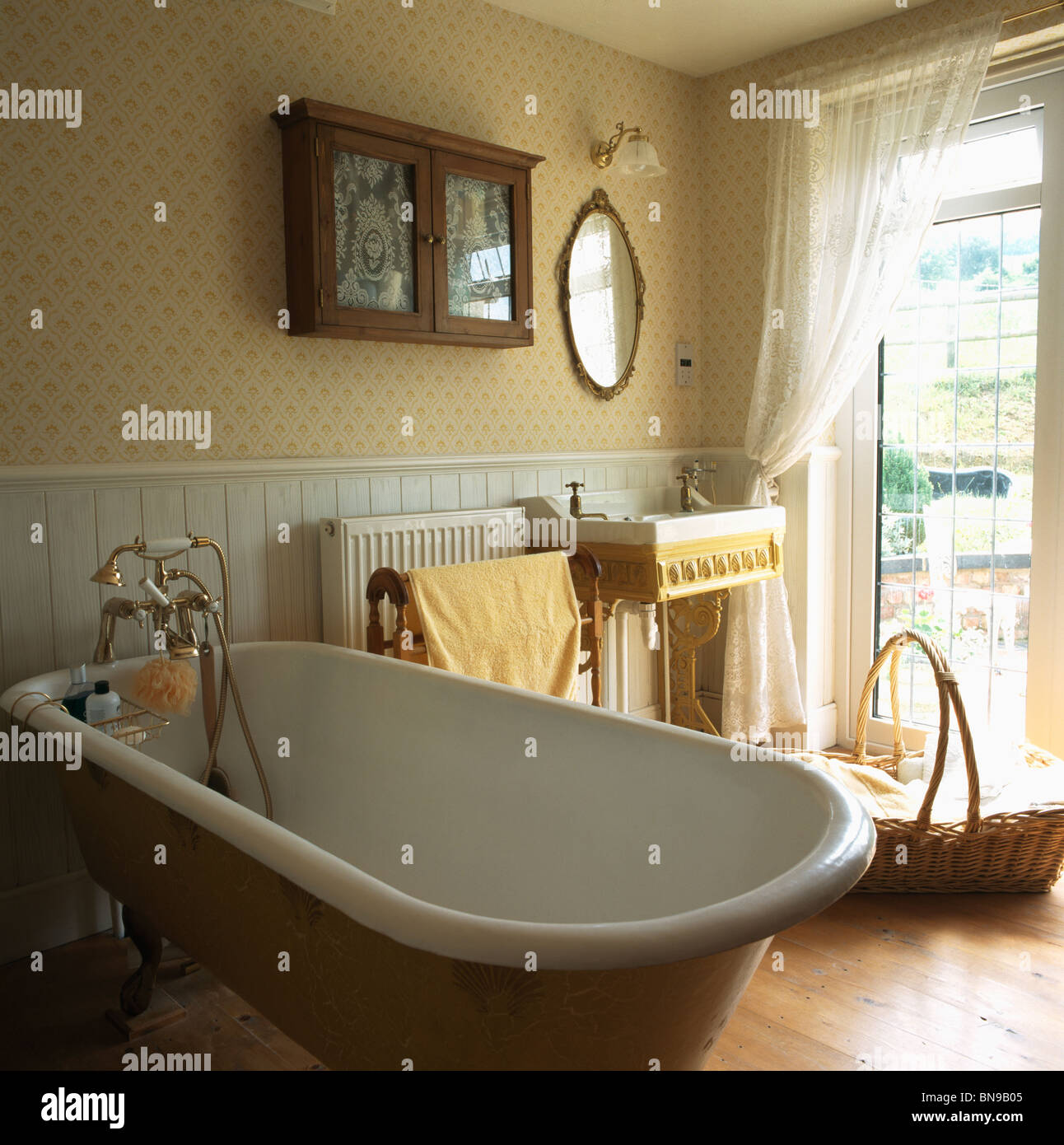 Une baignoire dans la salle de bain traditionnelle avec papier peint à  motifs et des fenêtres à la française à côté d''un évier Photo Stock - Alamy