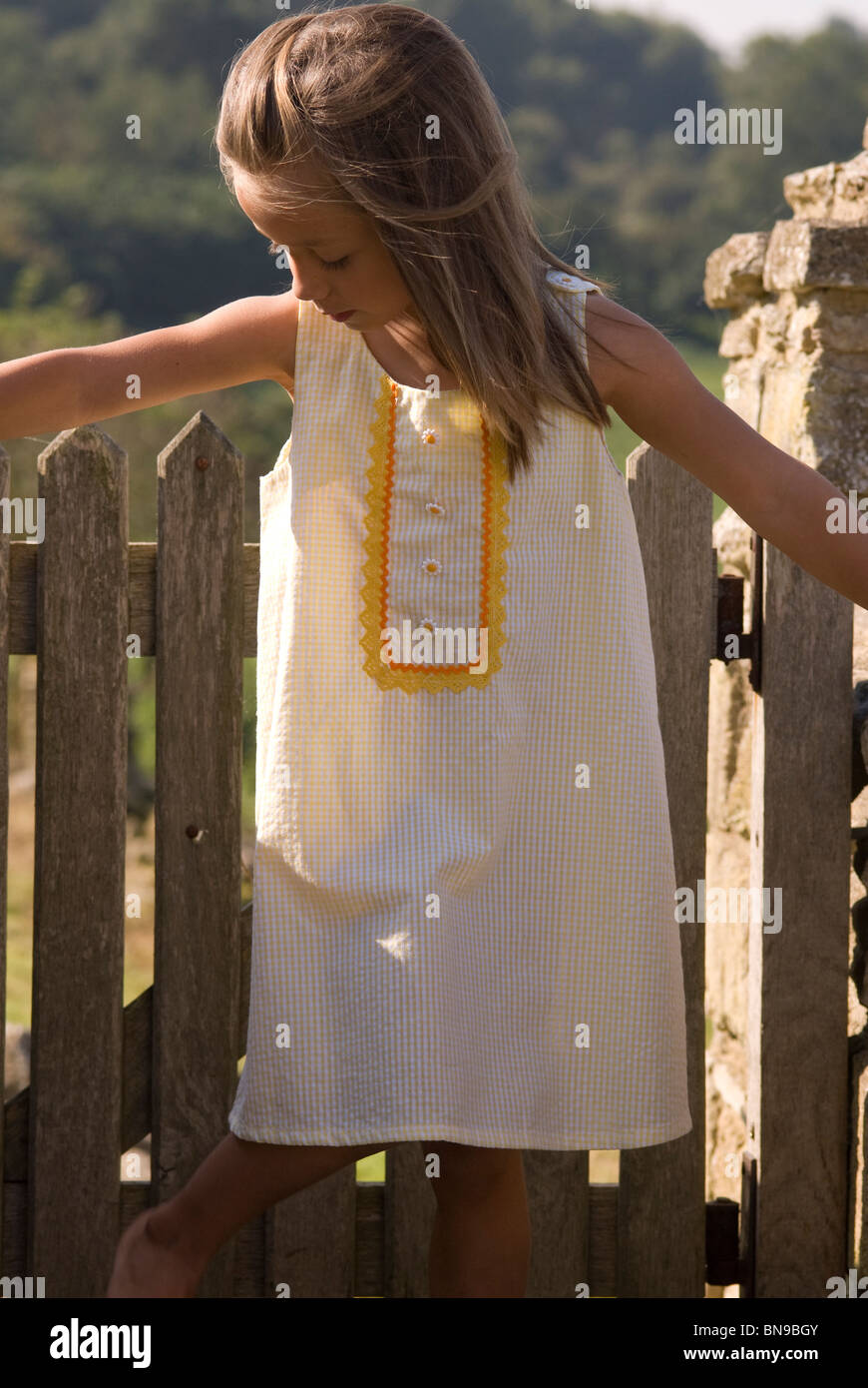 Petite fille aux longs cheveux bruns portant une robe d'été jaune Banque D'Images